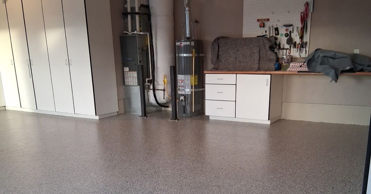 Garage interior with a shiny, speckled floor, storage cabinets, and a water heater.