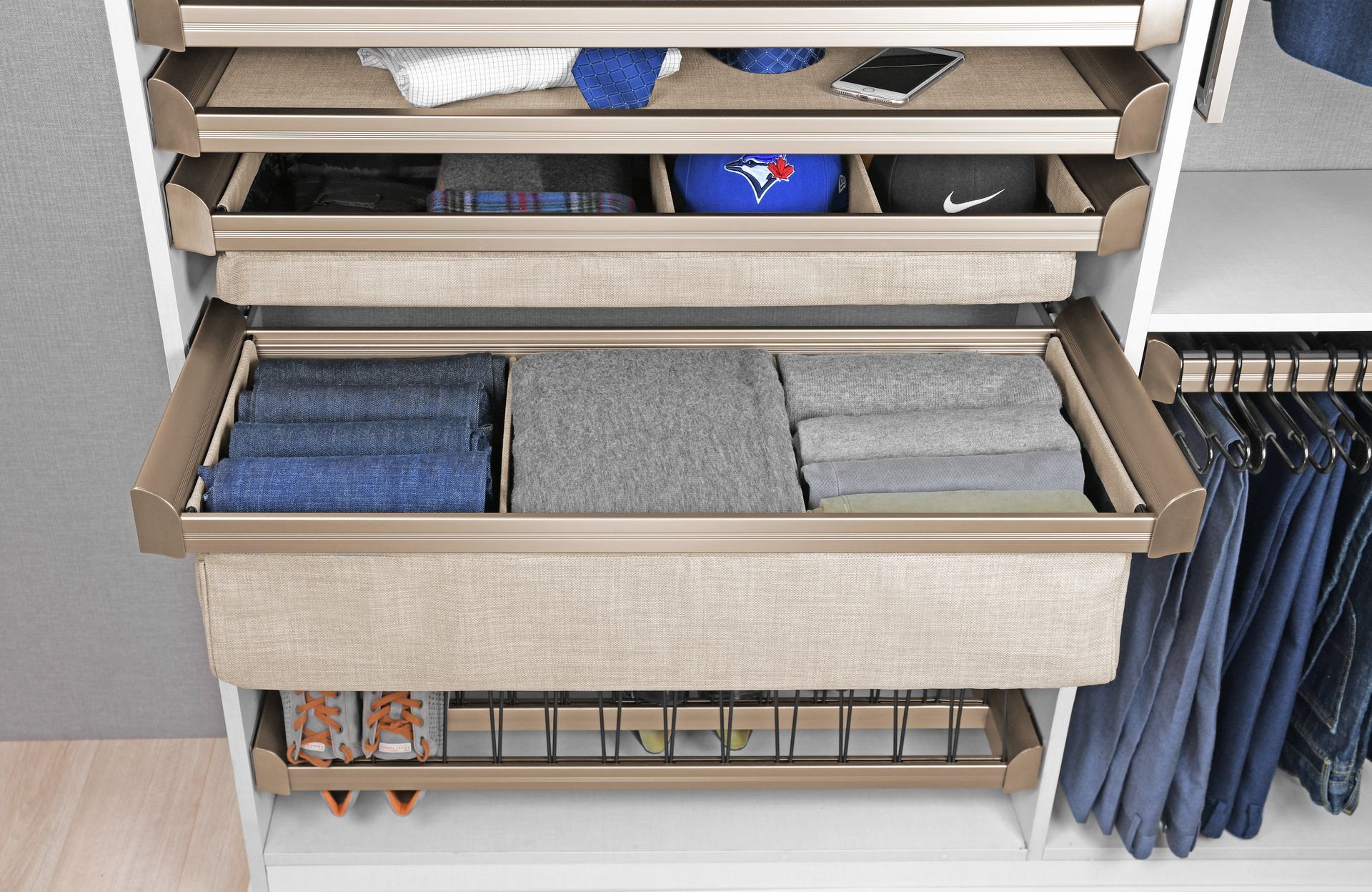 Closet with pull-out drawers. Drawers contain folded clothes, hats, a phone, and accessories.