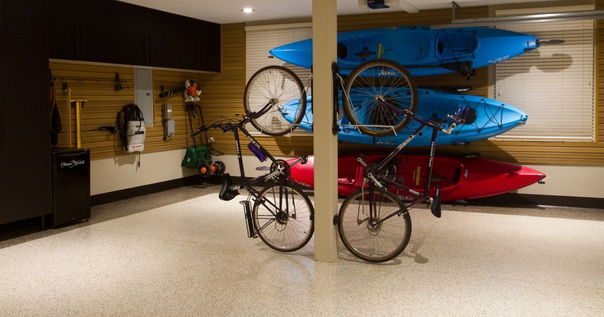 Garage with organized storage: kayaks on wall, bikes on rack, light epoxy floor.