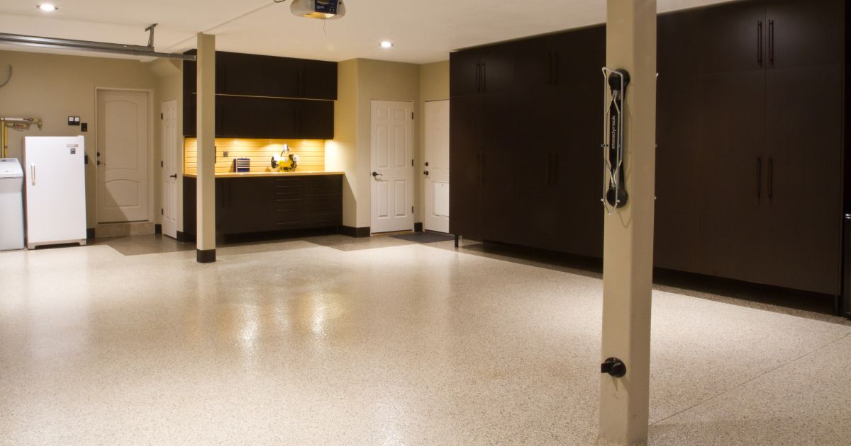 A classic car and several motorcycles on a speckled floor in a showroom.