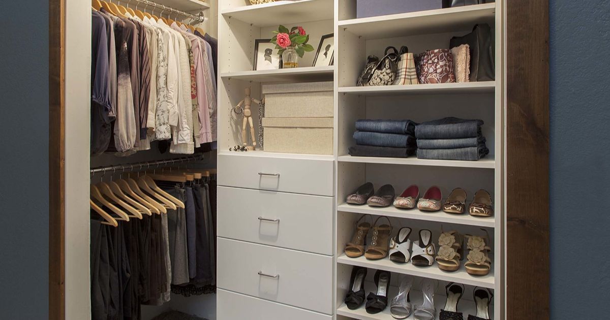 Walk-in closet with hanging clothes, shelves, and drawers. White shelves, neat organization.
