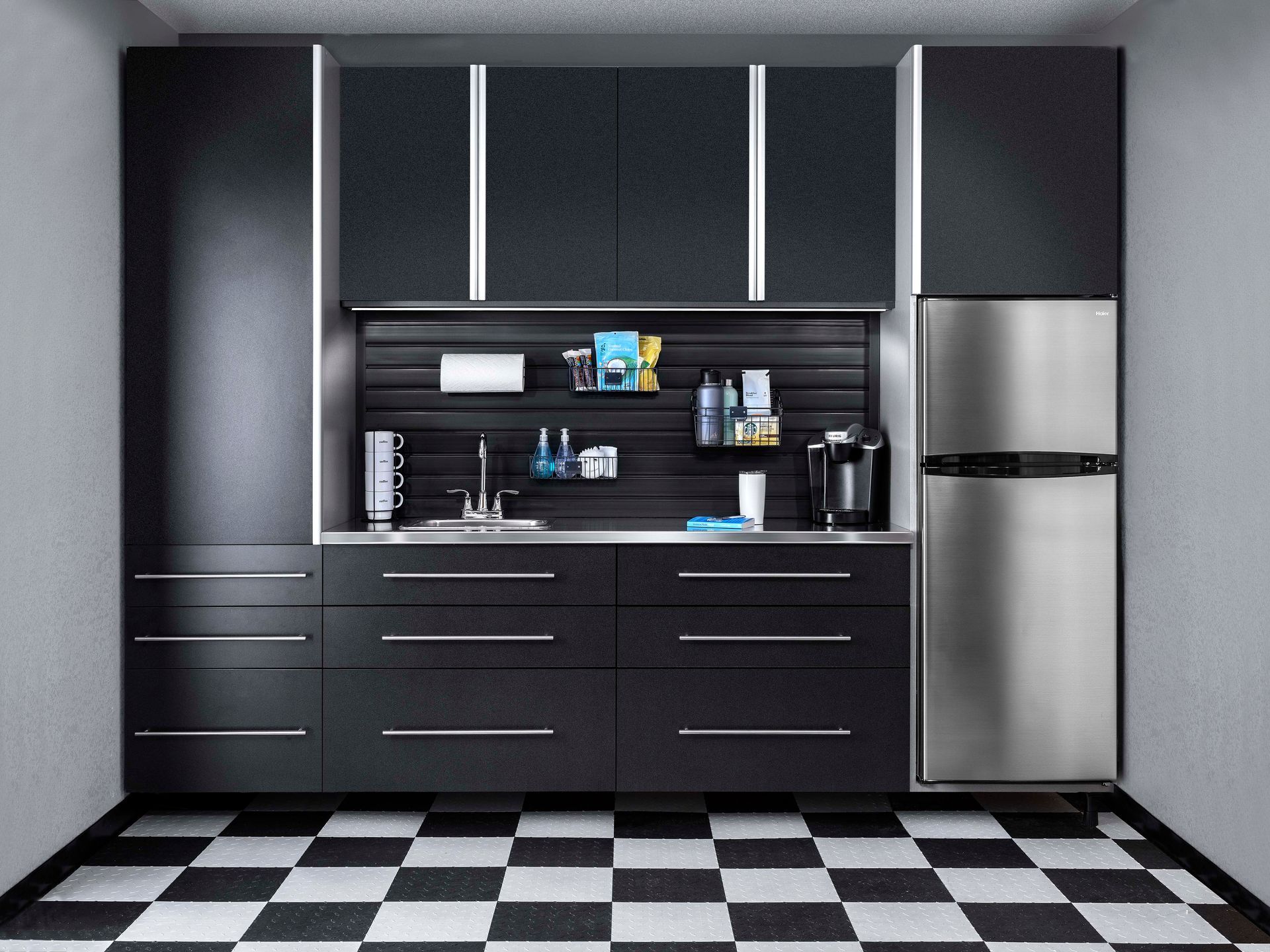 Black garage cabinets and fridge, with a sink and storage, black and white checkered floor.