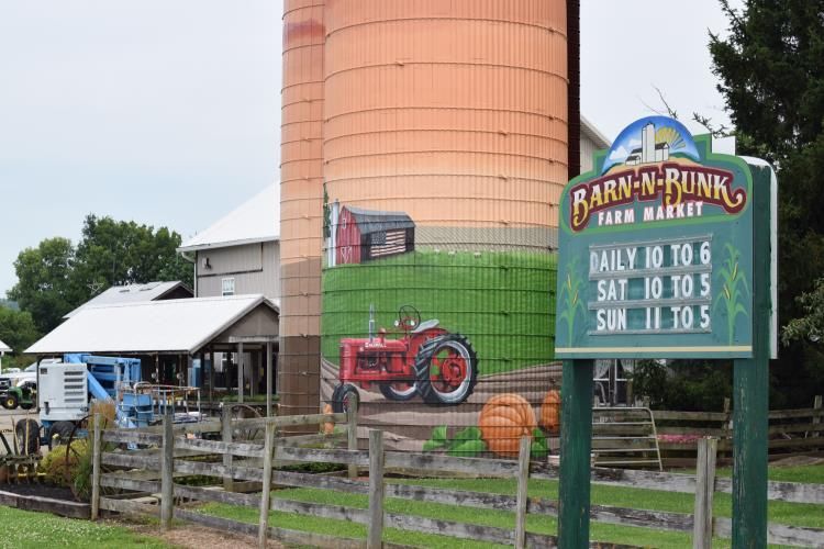 A sign for barn-n-rink farm market is in front of a silo.