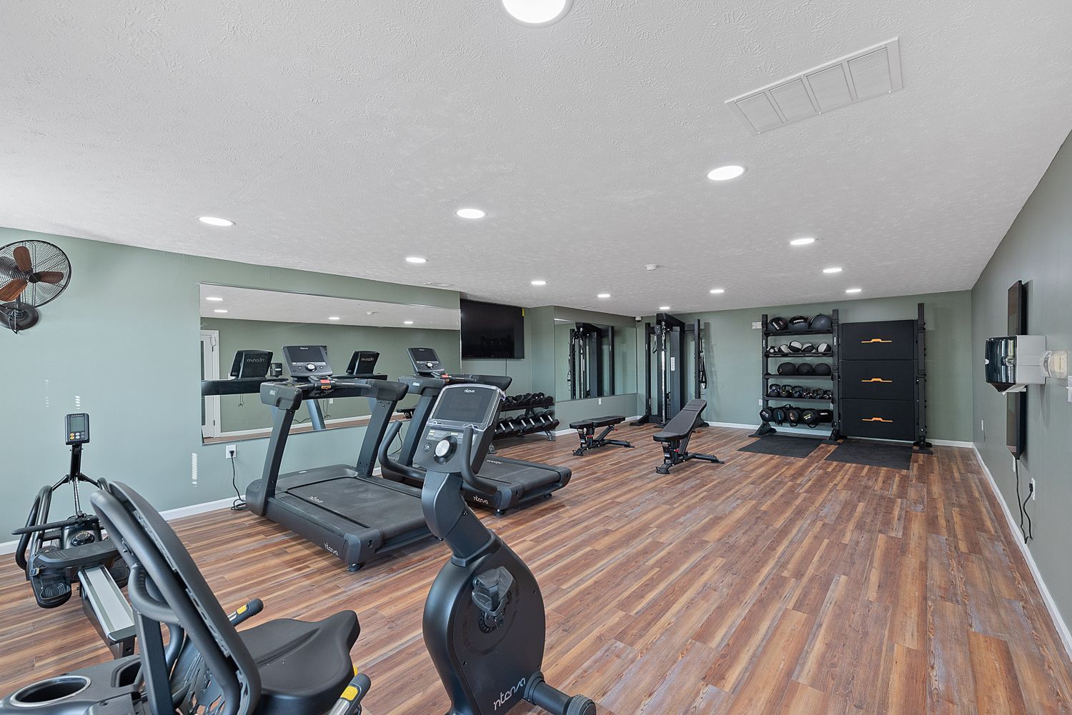 A large gym with treadmills , exercise bikes , and a mirror.
