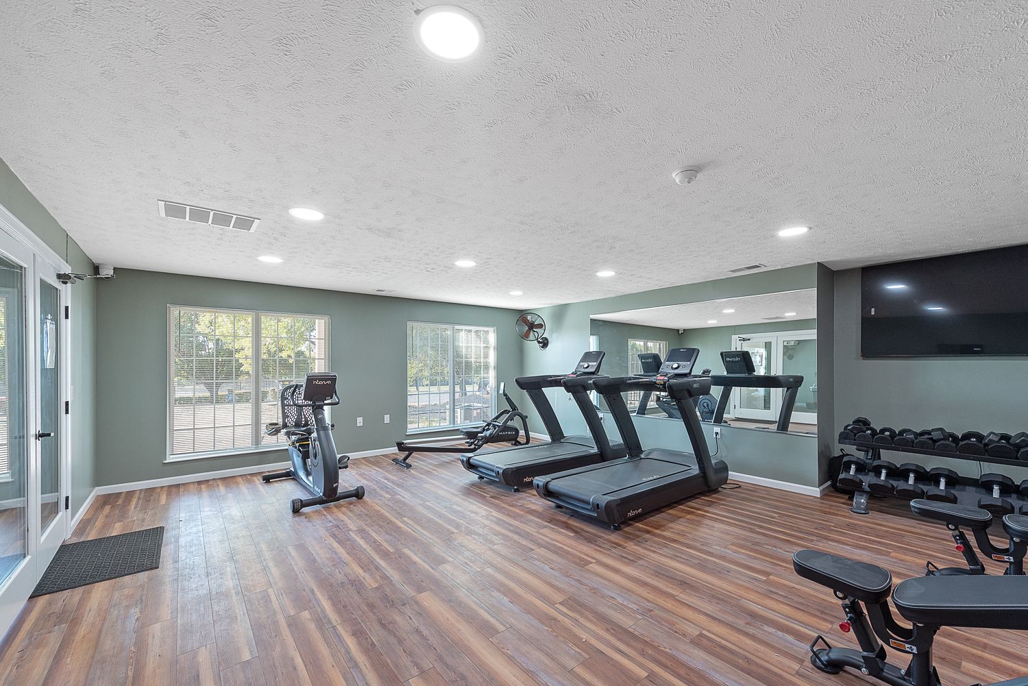 A large gym with treadmills , exercise bikes , and dumbbells.