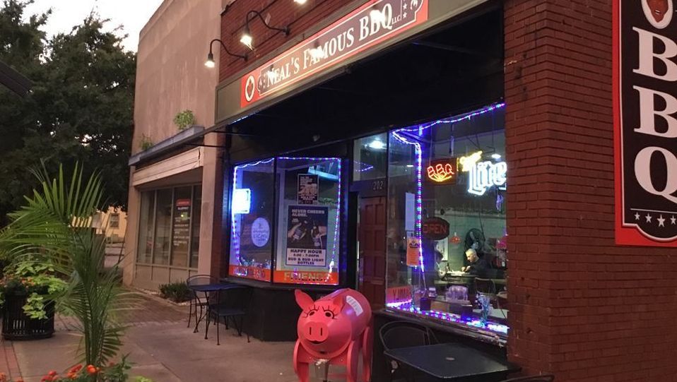 A restaurant with a pink pig statue in front of it.