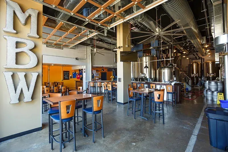 A large room with tables and chairs in a brewery.