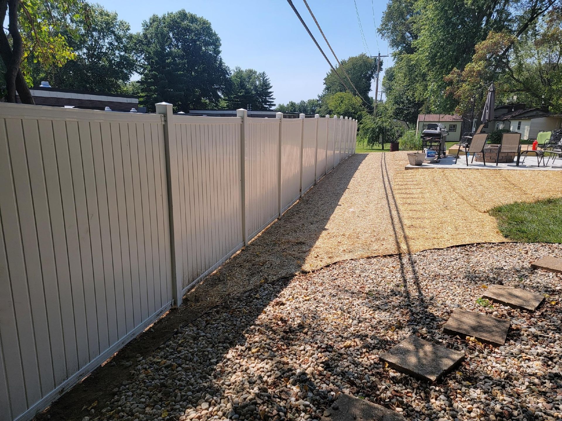 A fence surrounds a swimming pool in front of a house.