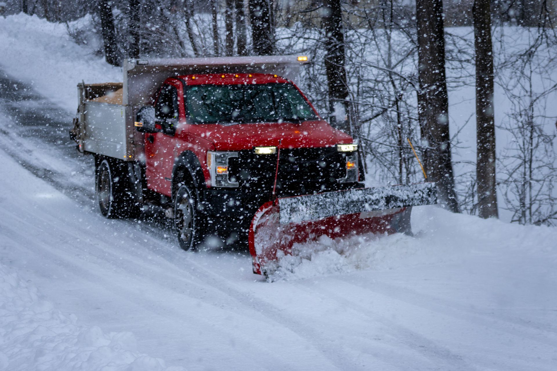 A yellow snow plow is clearing snow from a road.