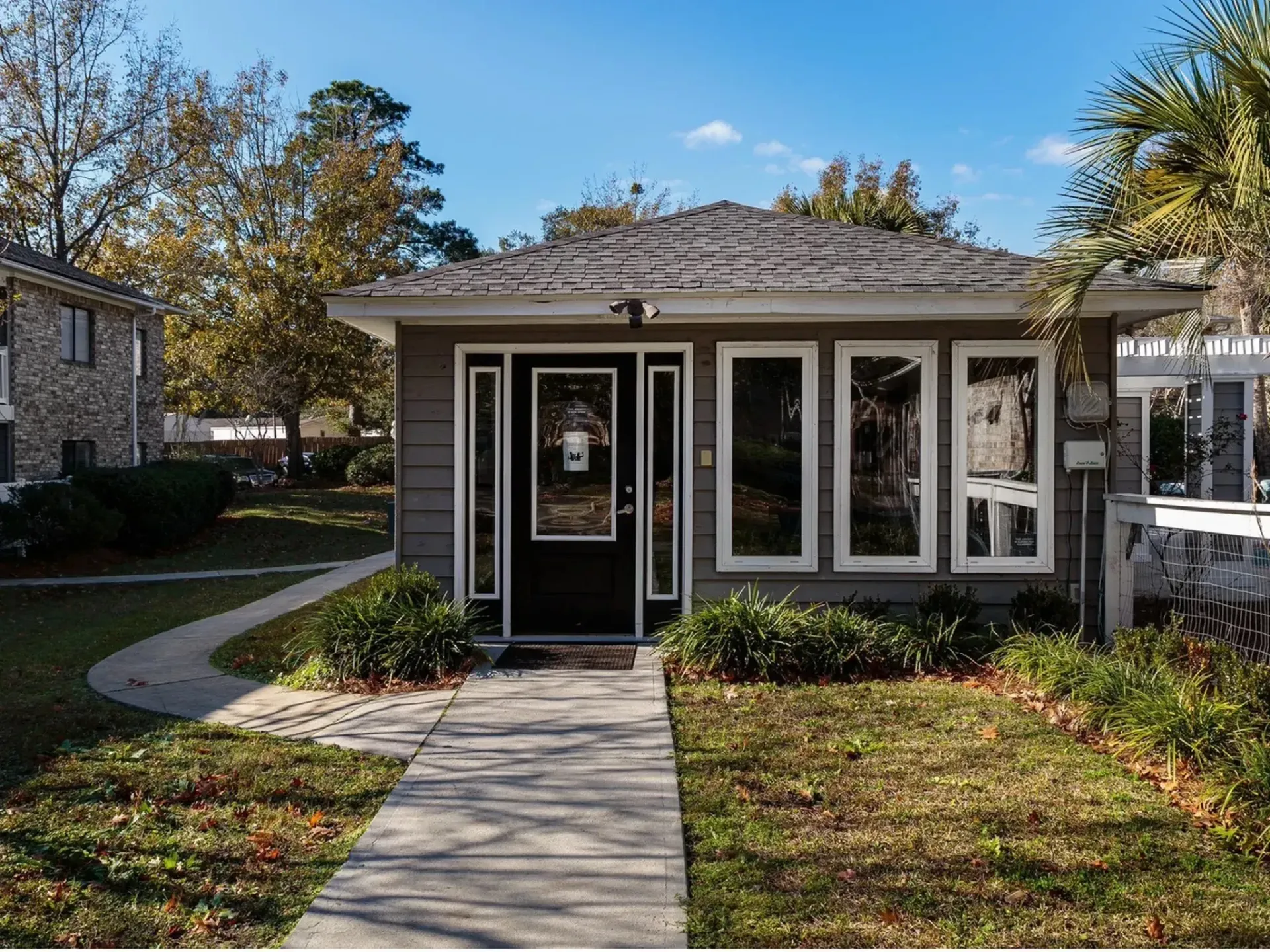 Exterior view of a building entrance with landscaped pathway and windows.