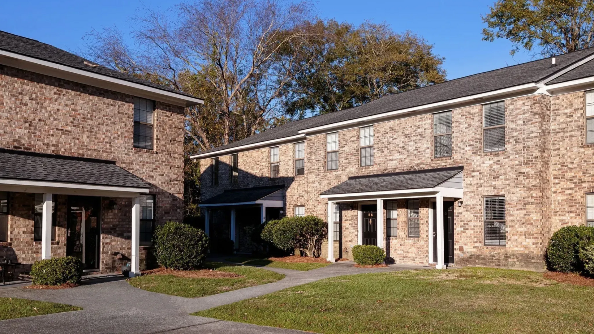 Exterior view of brick apartment buildings with pathways and greenery.
