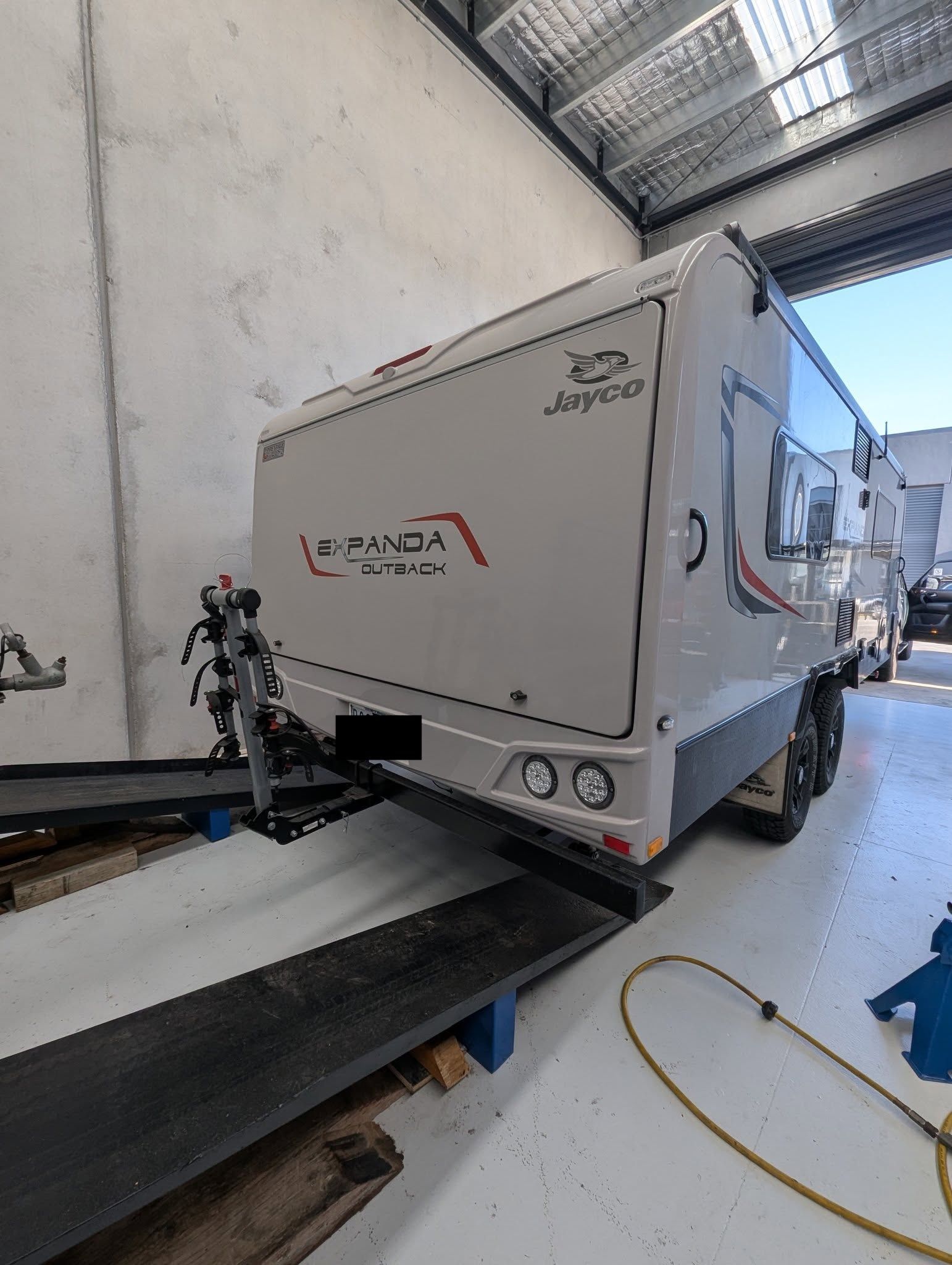 White caravan with red and black accents parked inside a warehouse. — Caravan and Trailer Clinic Geelong in Breakwater, VIC