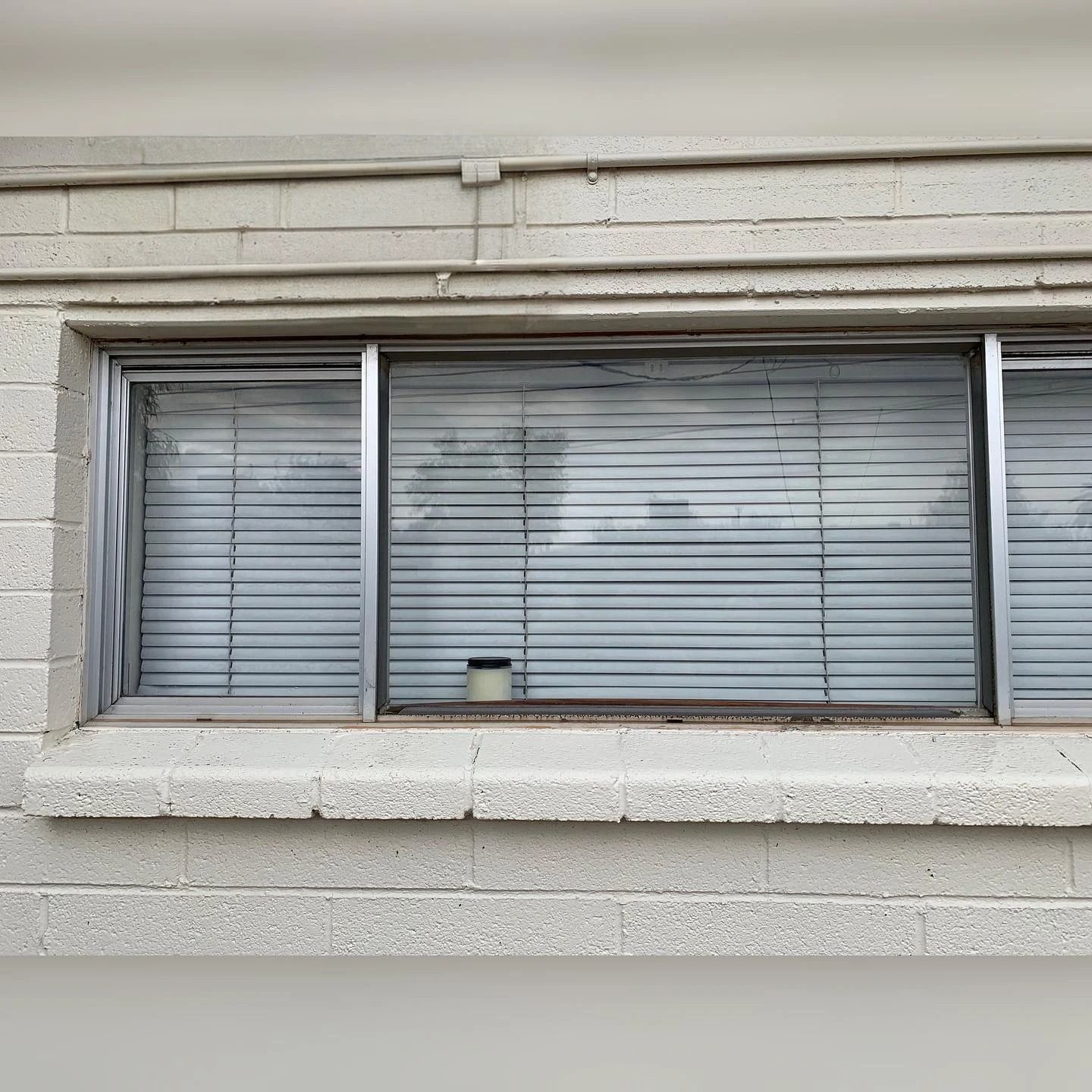 A window with blinds on it is on a brick building.
