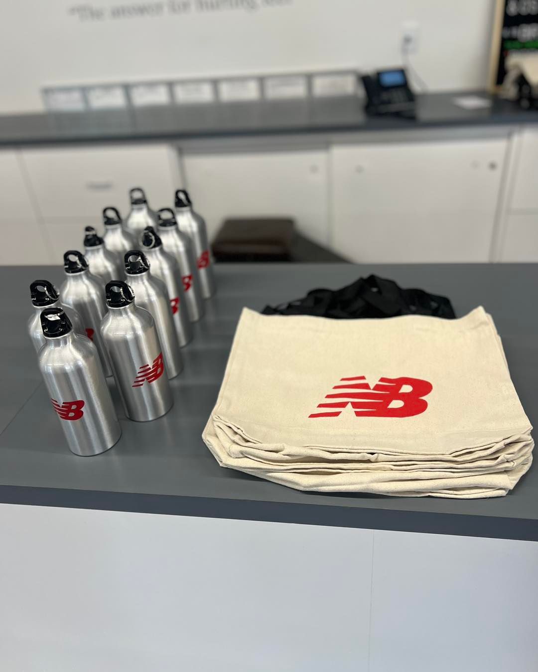 A stack of new balance bags and water bottles on a counter