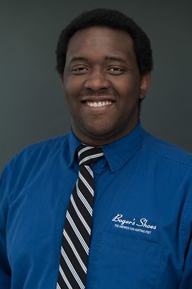 A man wearing a blue shirt and tie is smiling for the camera.