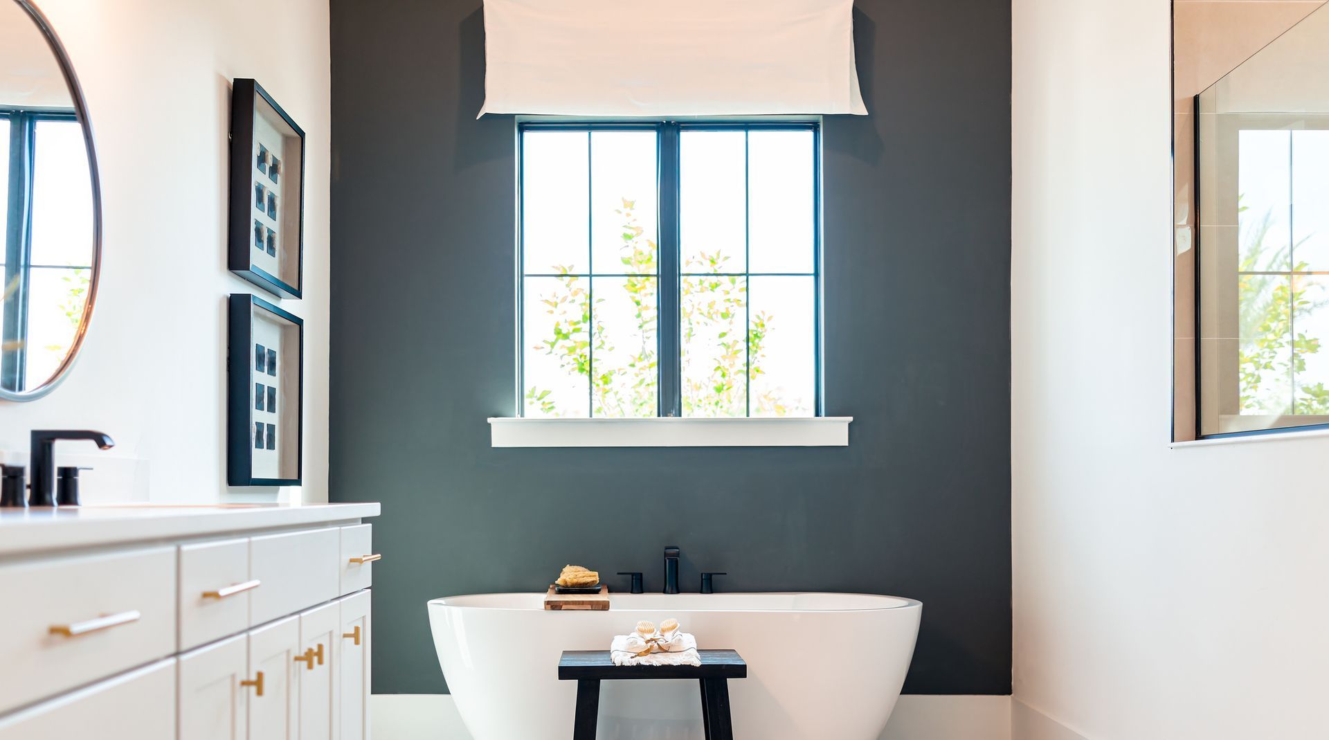 A bathroom with a tub , sink , mirror and window.