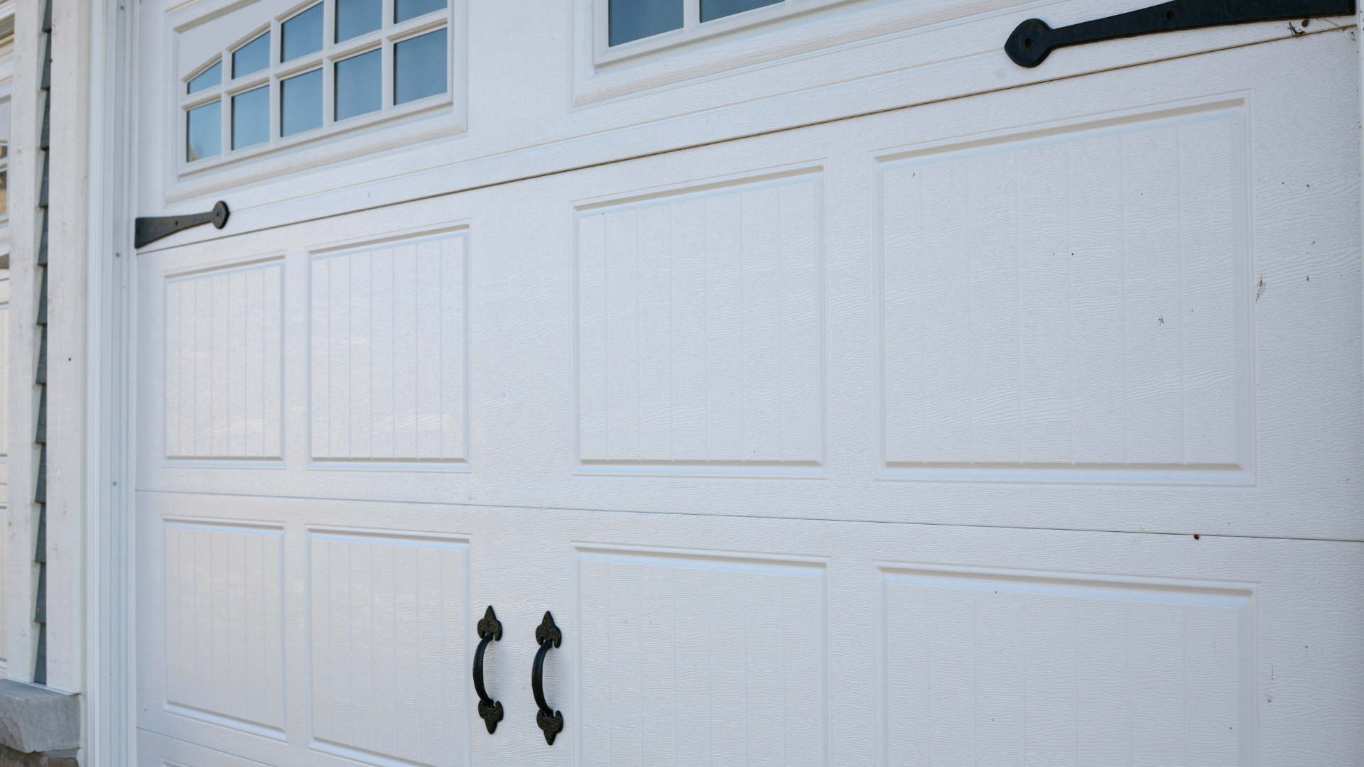 A white garage door with black handles and a window.