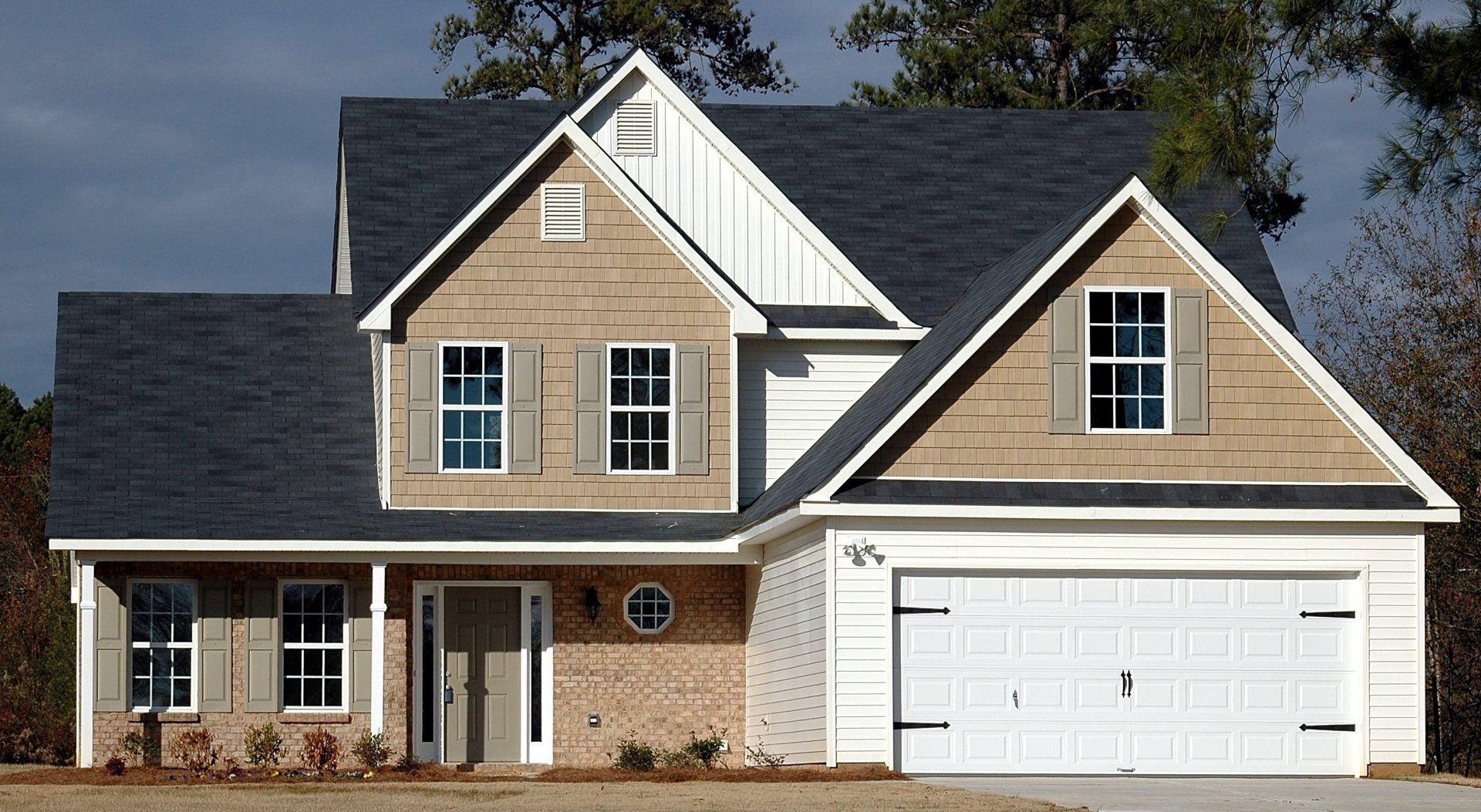 A large house with a white garage door and a black roof