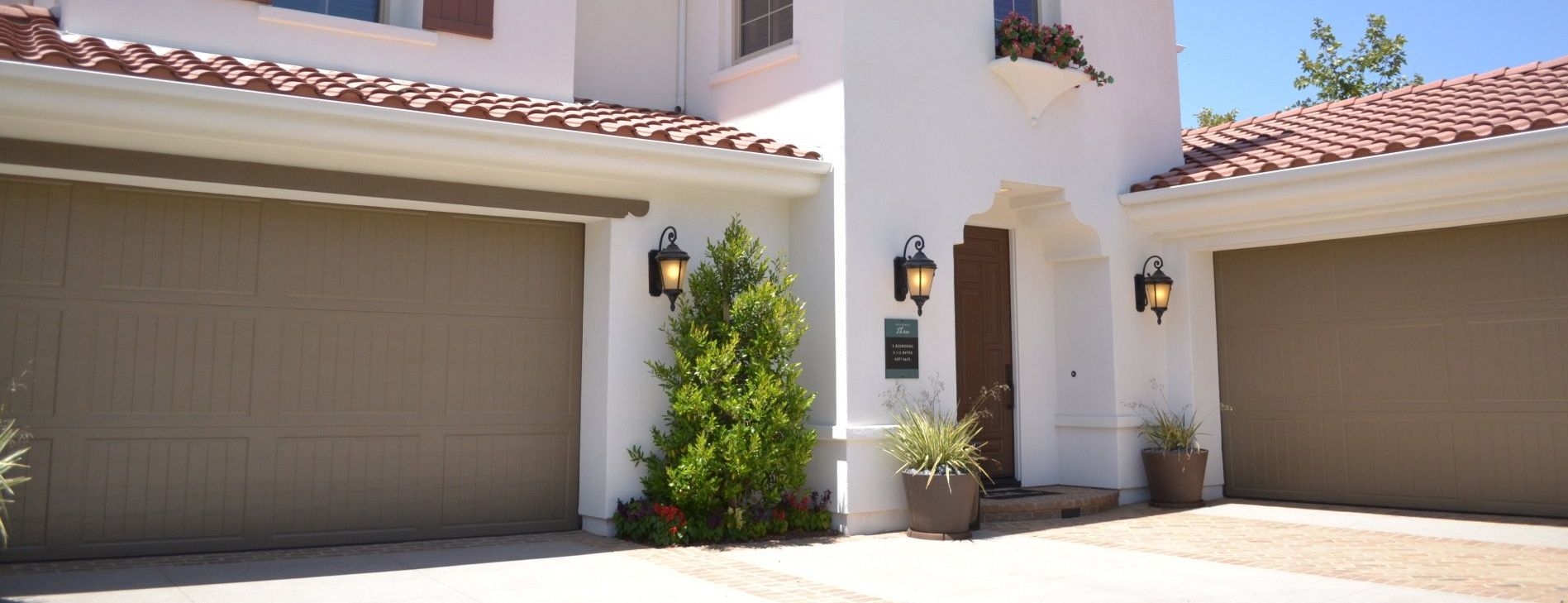 A white house with brown garage doors and a tiled roof