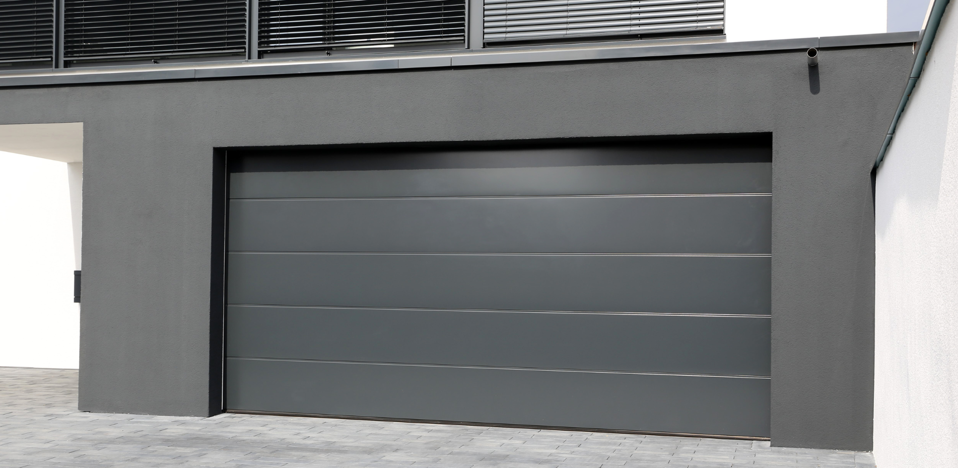 A gray, sectional garage door is sitting on the side of a building.