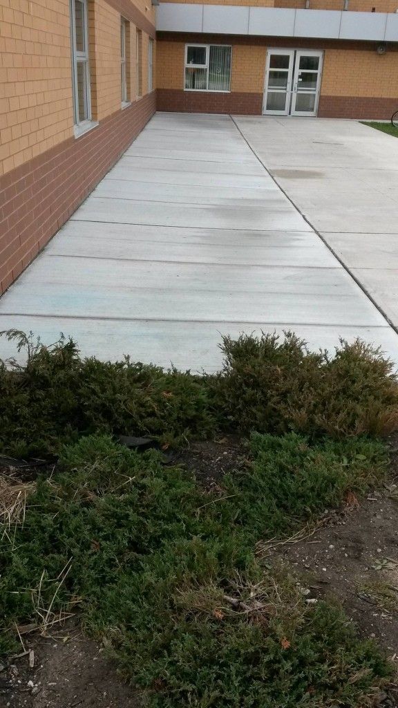 A brick building with a concrete walkway in front of it.