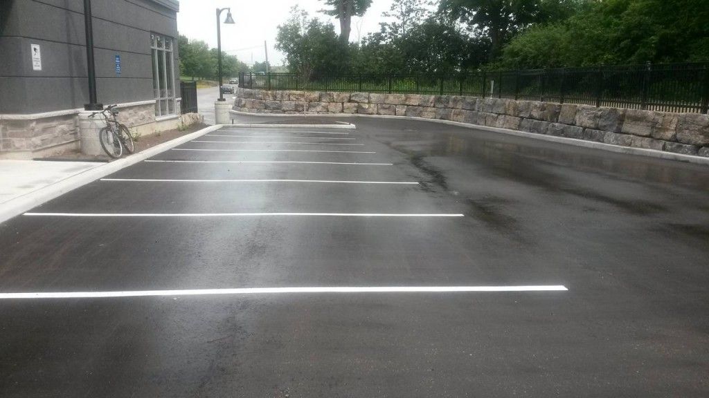 A parking lot with white lines and a stone wall.