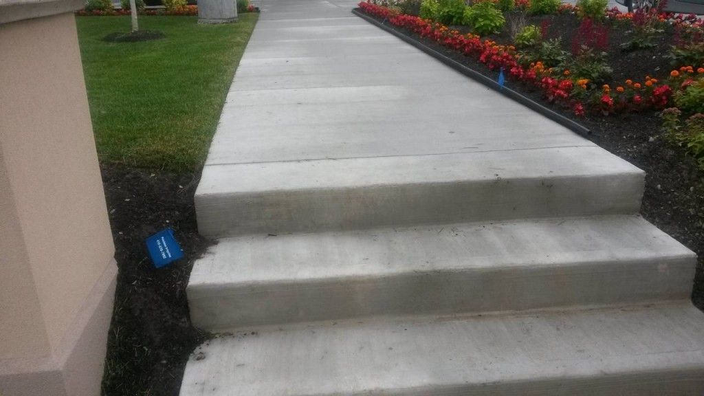A concrete walkway with steps leading up to a garden.