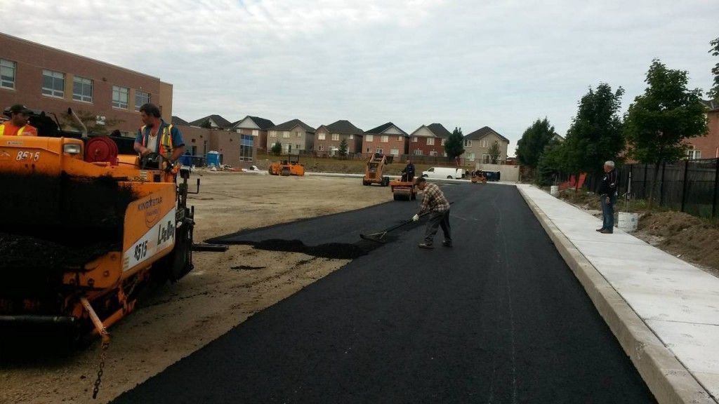 A road is being paved with a yellow machine that says ' asphalt ' on it