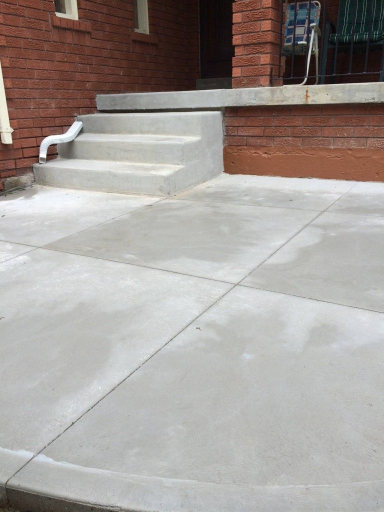A concrete walkway with stairs leading up to a brick building.