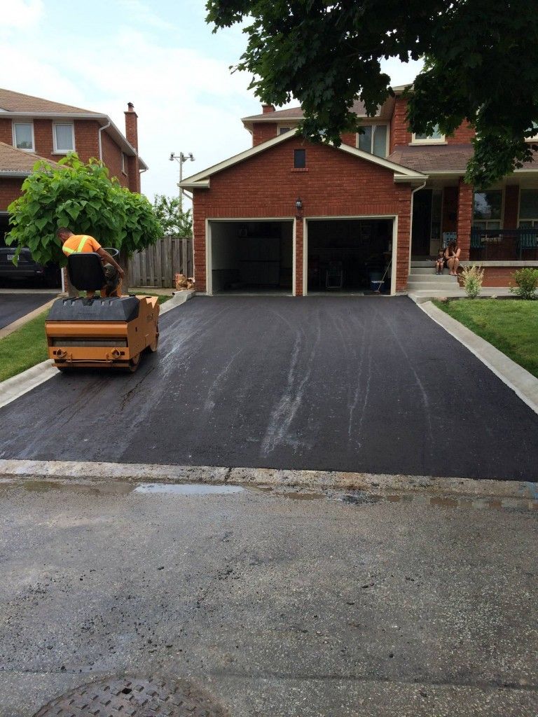 A driveway is being paved in front of a brick house