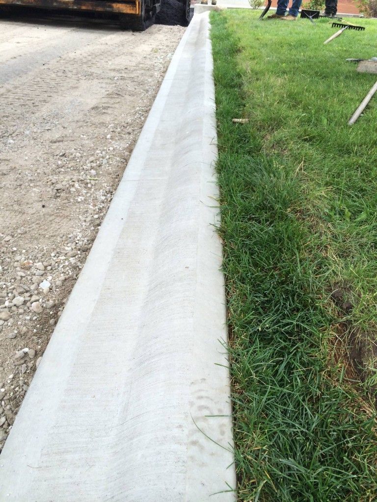 A concrete curb is being installed next to a lush green lawn.