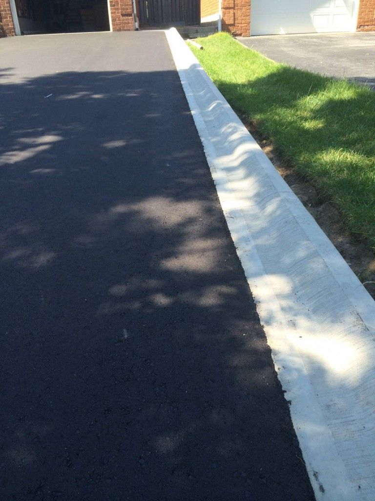 A driveway with a white curb and grass on the side