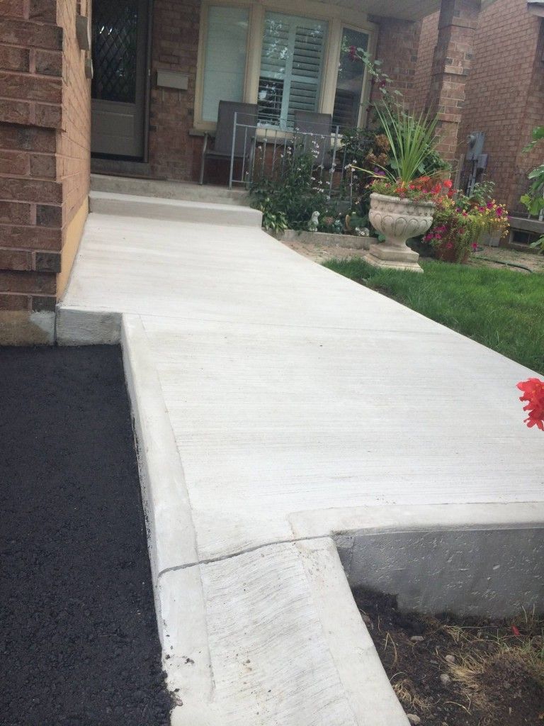 A concrete walkway leading to the front door of a house.