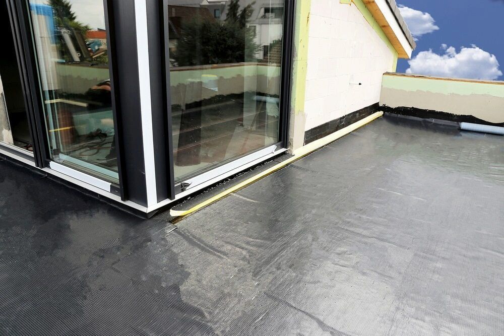 Black Roofing Membrane Installed on a Flat Roof Next to a Glass Window — Unique Waterproofing Solutions in North Rocks, NSW