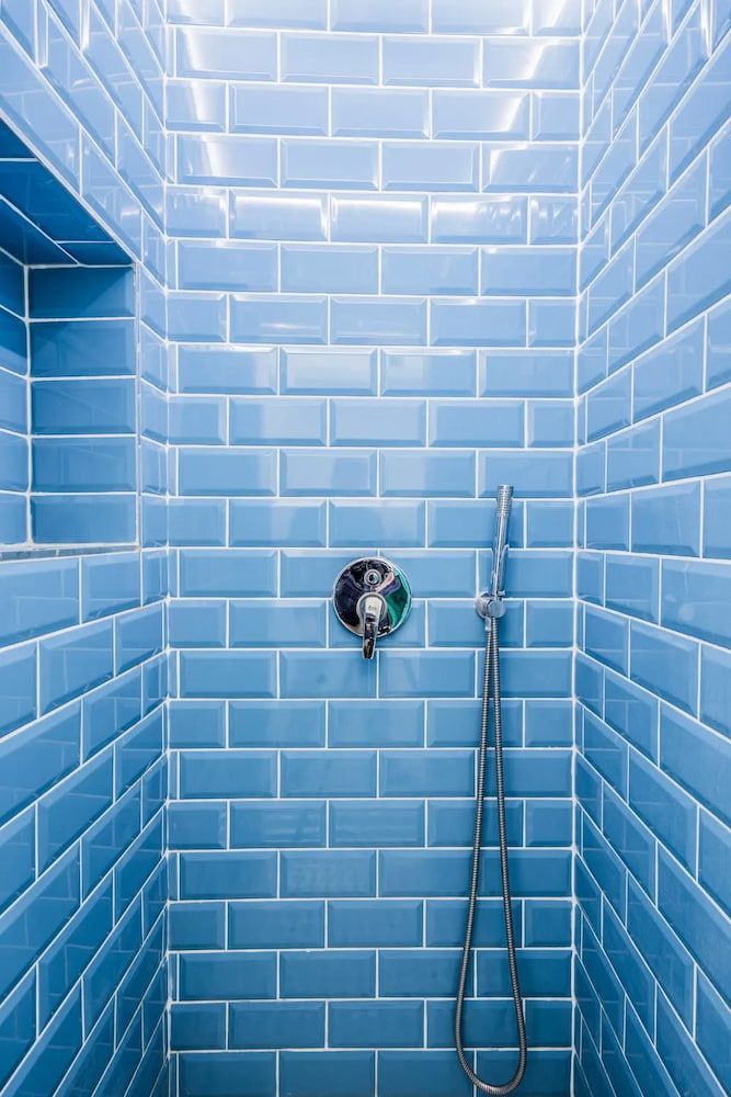 Blue tiled shower with a niche and showerhead. — Unique Waterproofing Solutions in North Rocks, NSW