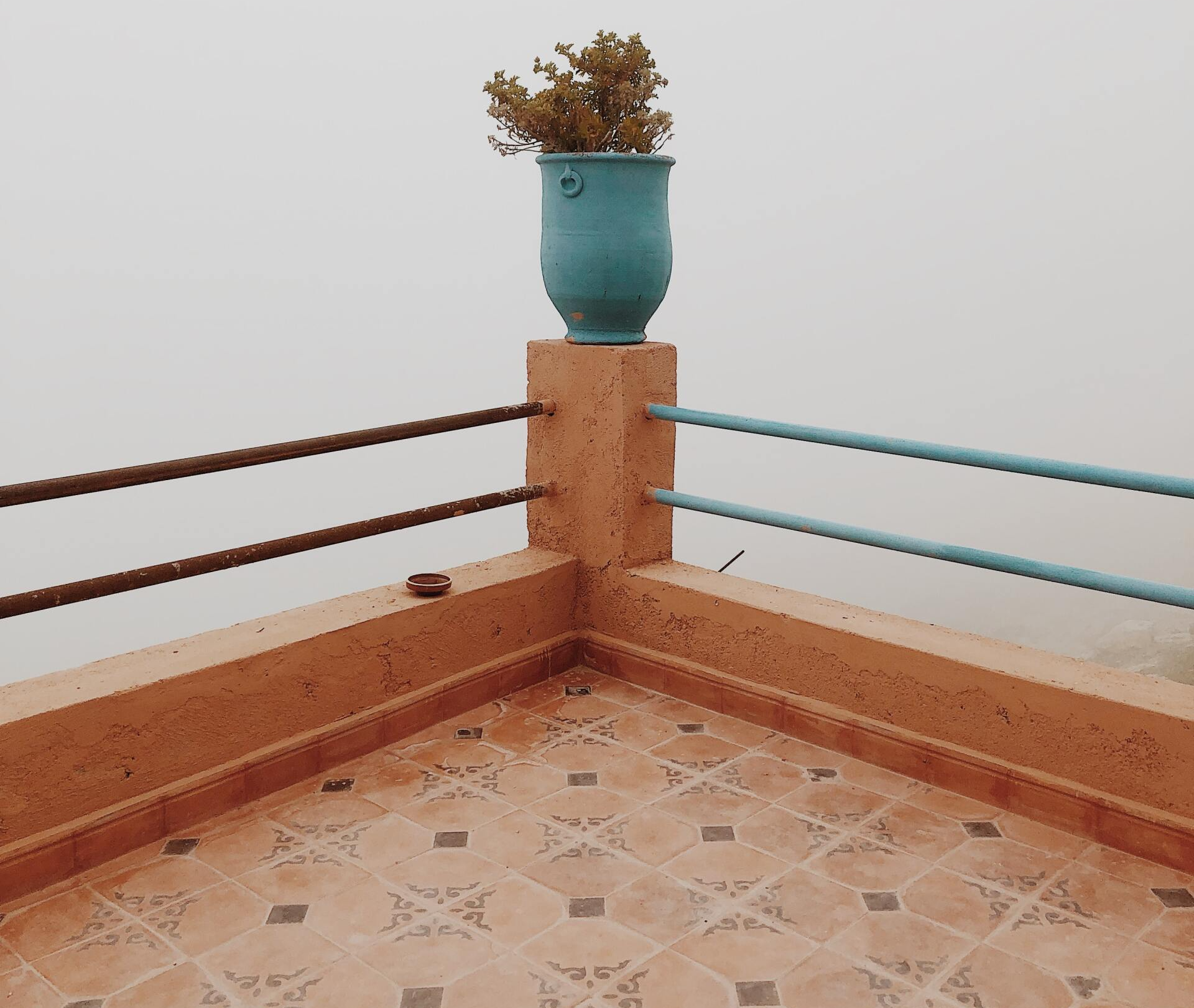 Terrace corner with brown tile, turquoise pot with plant, and brown and blue railings against a cloudy sky. — Unique Waterproofing Solutions in North Rocks, NSW