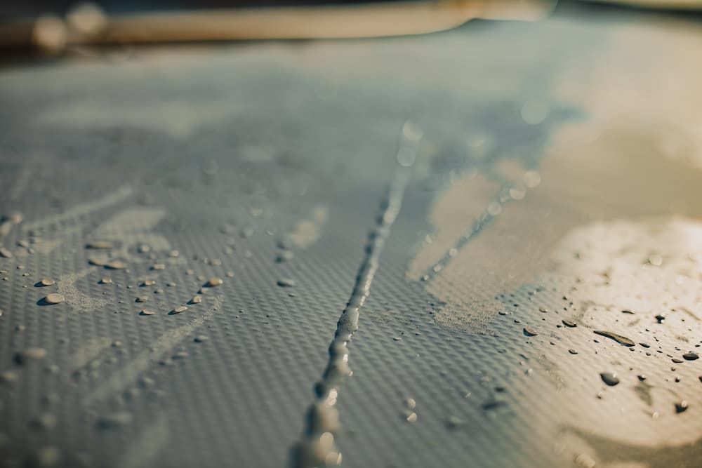 Close-up of a surface with a line of water droplets, speckled with smaller droplets. — Unique Waterproofing Solutions in North Rocks, NSW