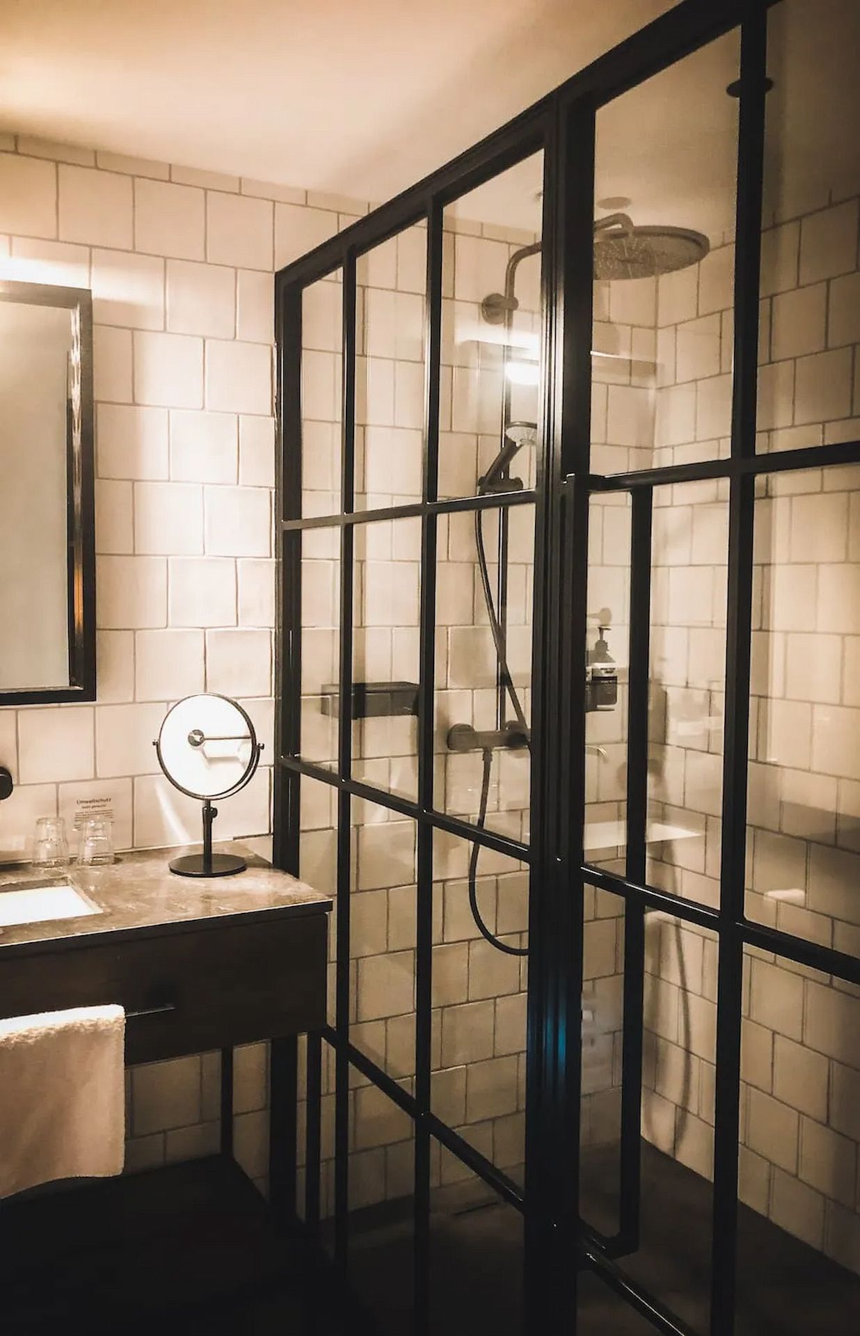 Modern bathroom with a glass-enclosed shower, white tile walls, and a dark-framed mirror and vanity. — Unique Waterproofing Solutions in North Rocks, NSW