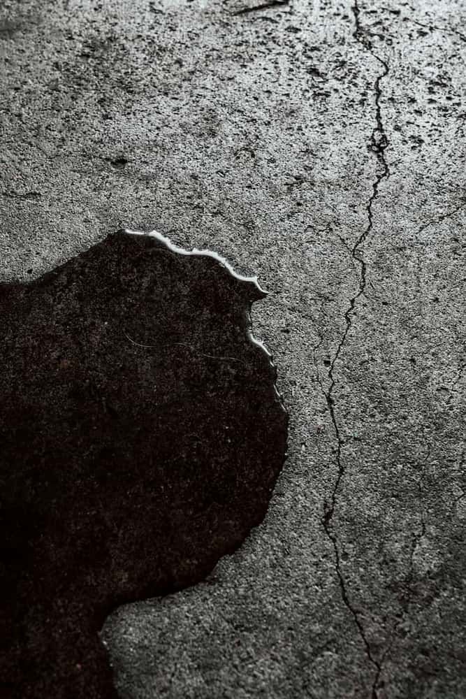 Dark liquid stain on a cracked gray concrete surface. — Unique Waterproofing Solutions in North Rocks, NSW
