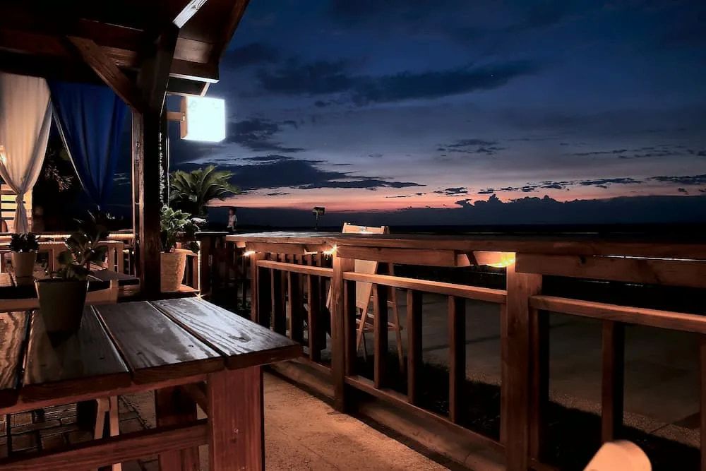 Wooden Deck With Tables and Railing Overlooking the Ocean at Dusk — Unique Waterproofing Solutions in North Rocks, NSW