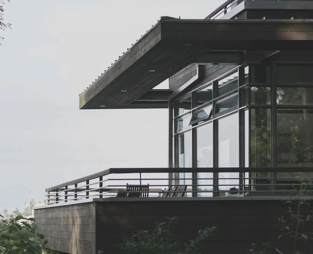 Modern house with a dark facade, large windows, and a balcony overlooking a landscape. — Unique Waterproofing Solutions in North Rocks, NSW