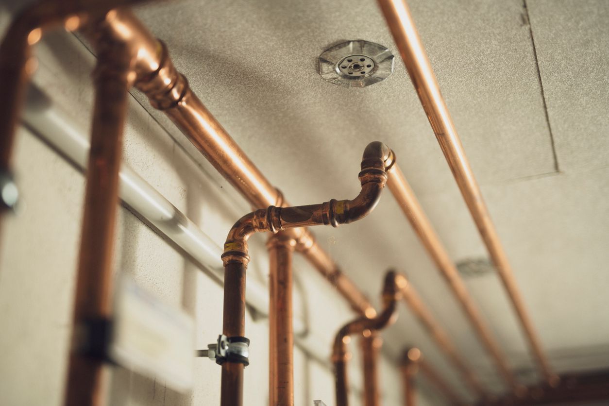 A row of copper pipes hanging from the ceiling in a room.