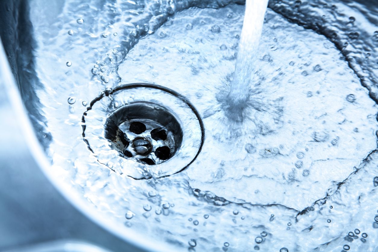 A close up of a sink with water running down the drain.