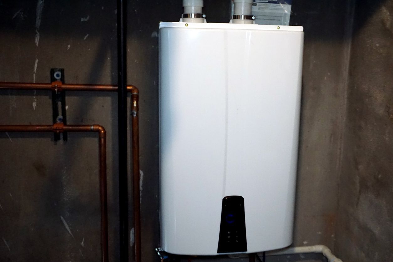 A white water heater is sitting in a room next to copper pipes.