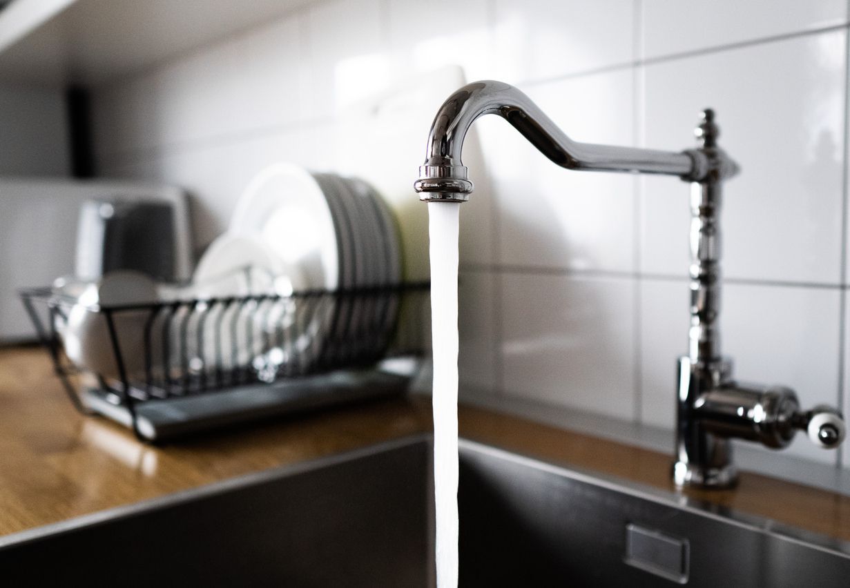 A kitchen sink with water running from the faucet