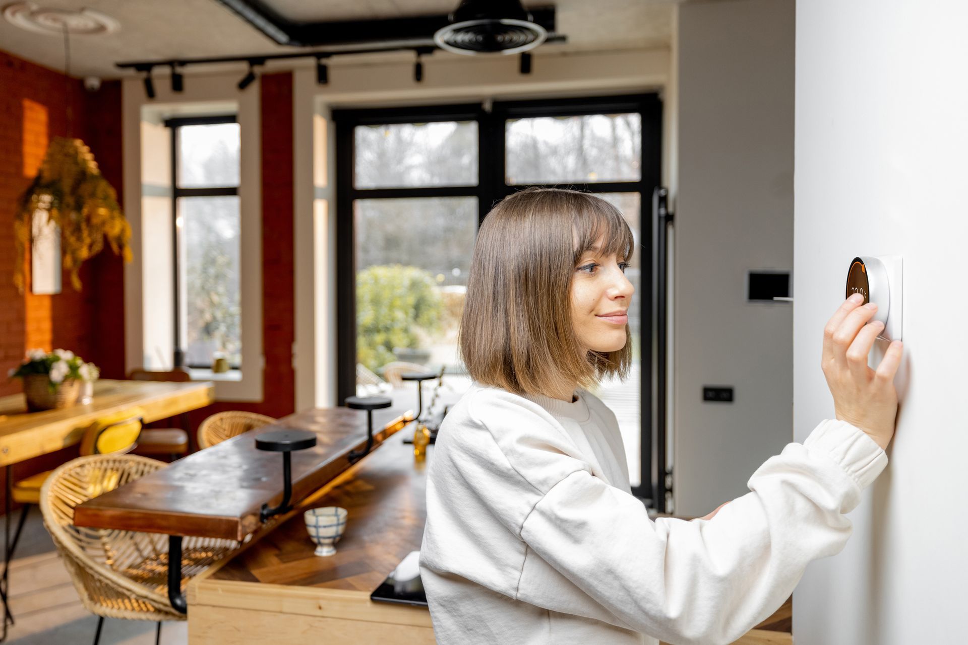 A woman is adjusting a light switch in a living room.