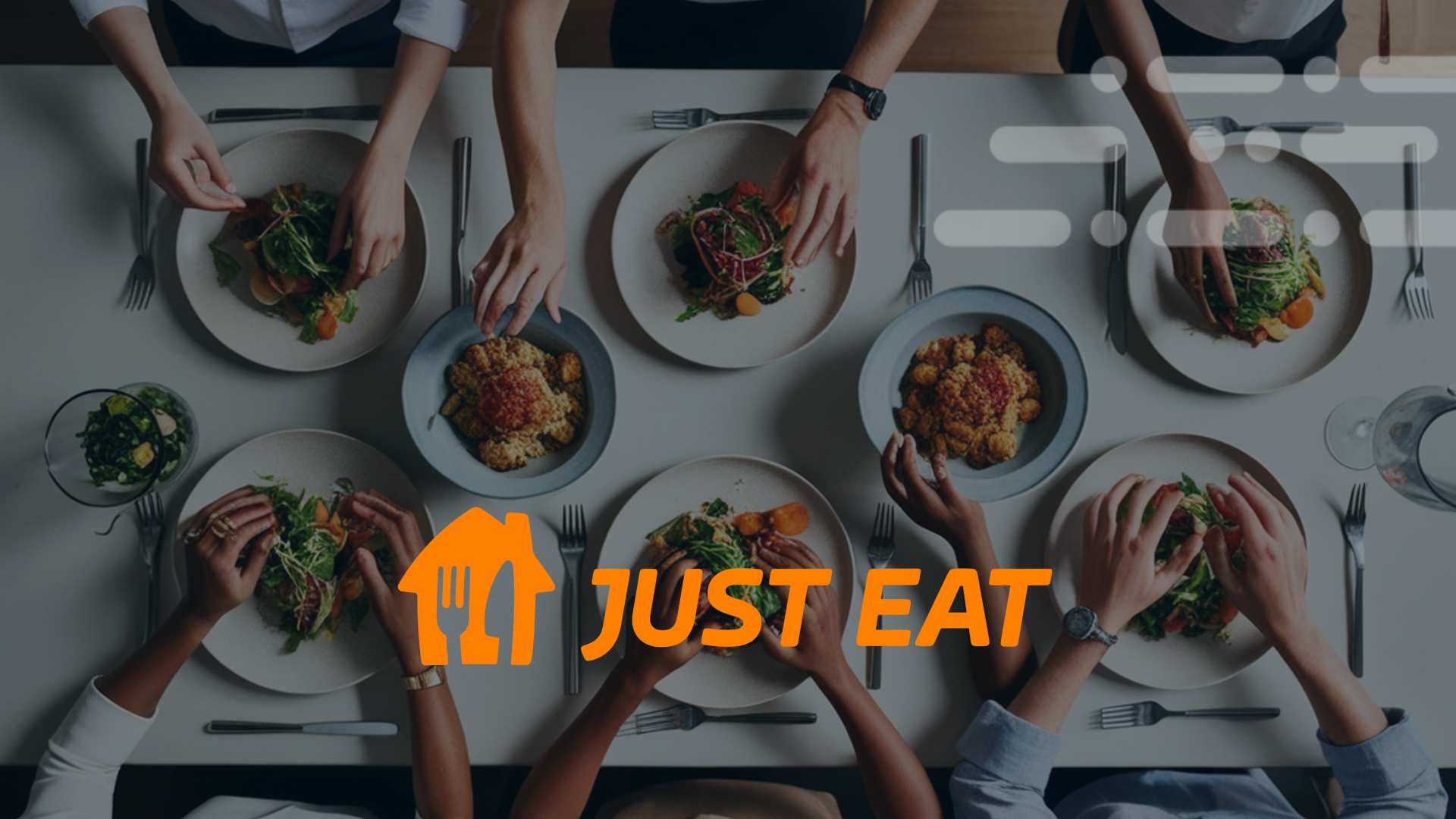 Overhead view of people eating together at a table, with orange Just Eat logo overlaid.