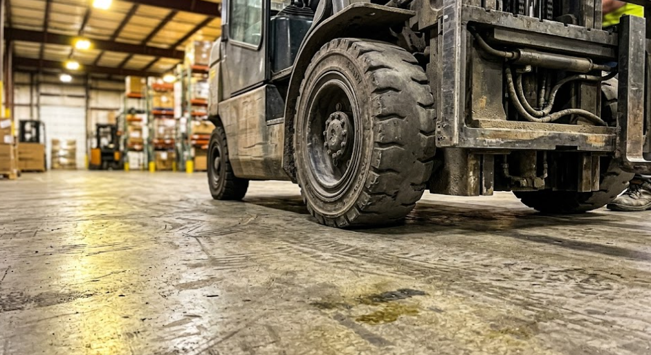 A forklift driving on a smooth, durable industrial commercial concrete warehouse floor.