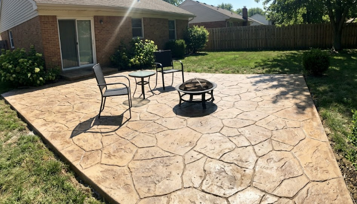 A decorative stamped concrete patio with outdoor furniture and a fire pit.