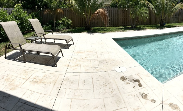 Safe and stylish stamped concrete pool deck resembling beautiful travertine tile.
